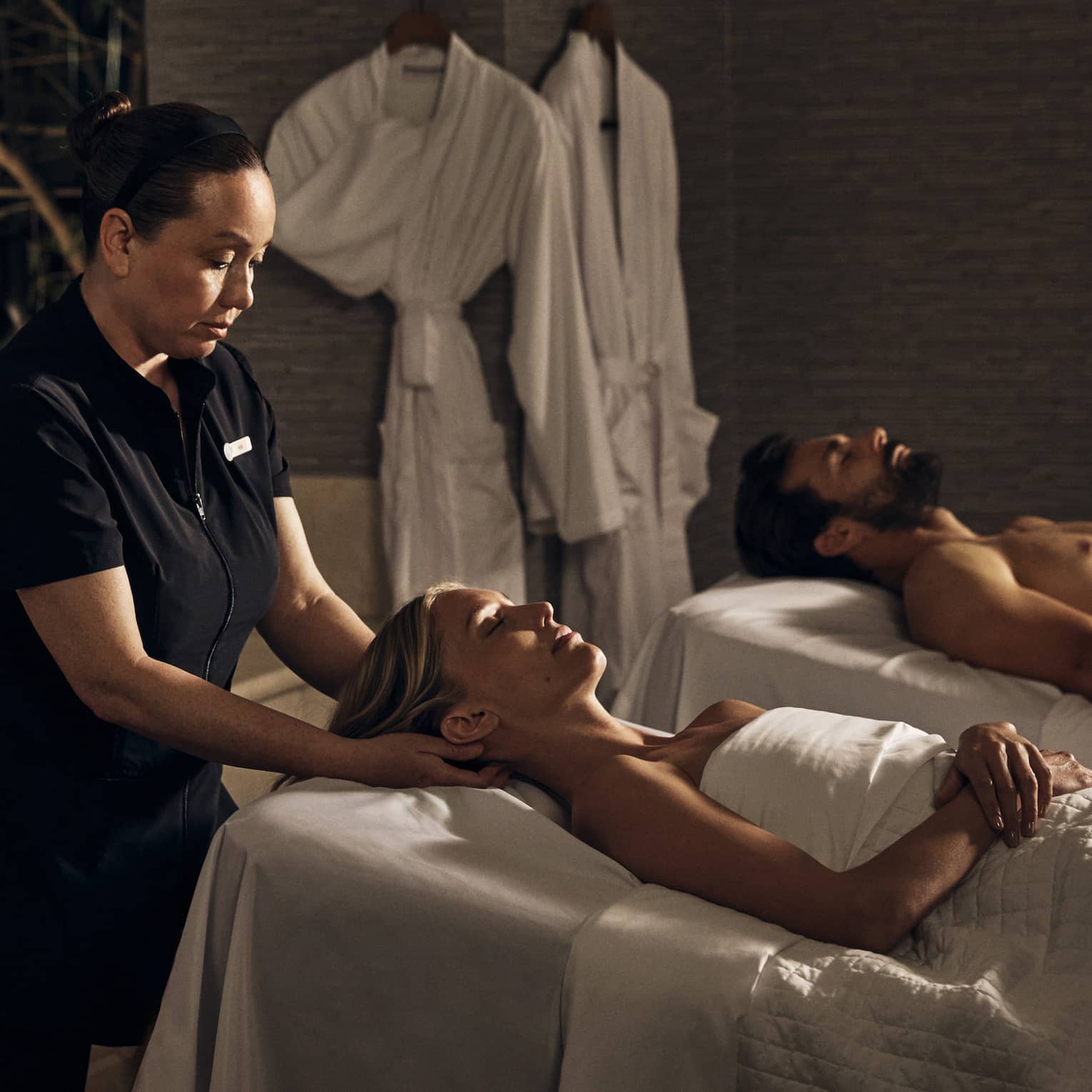 Two guests laying on massage tables in a room with a spa tub.