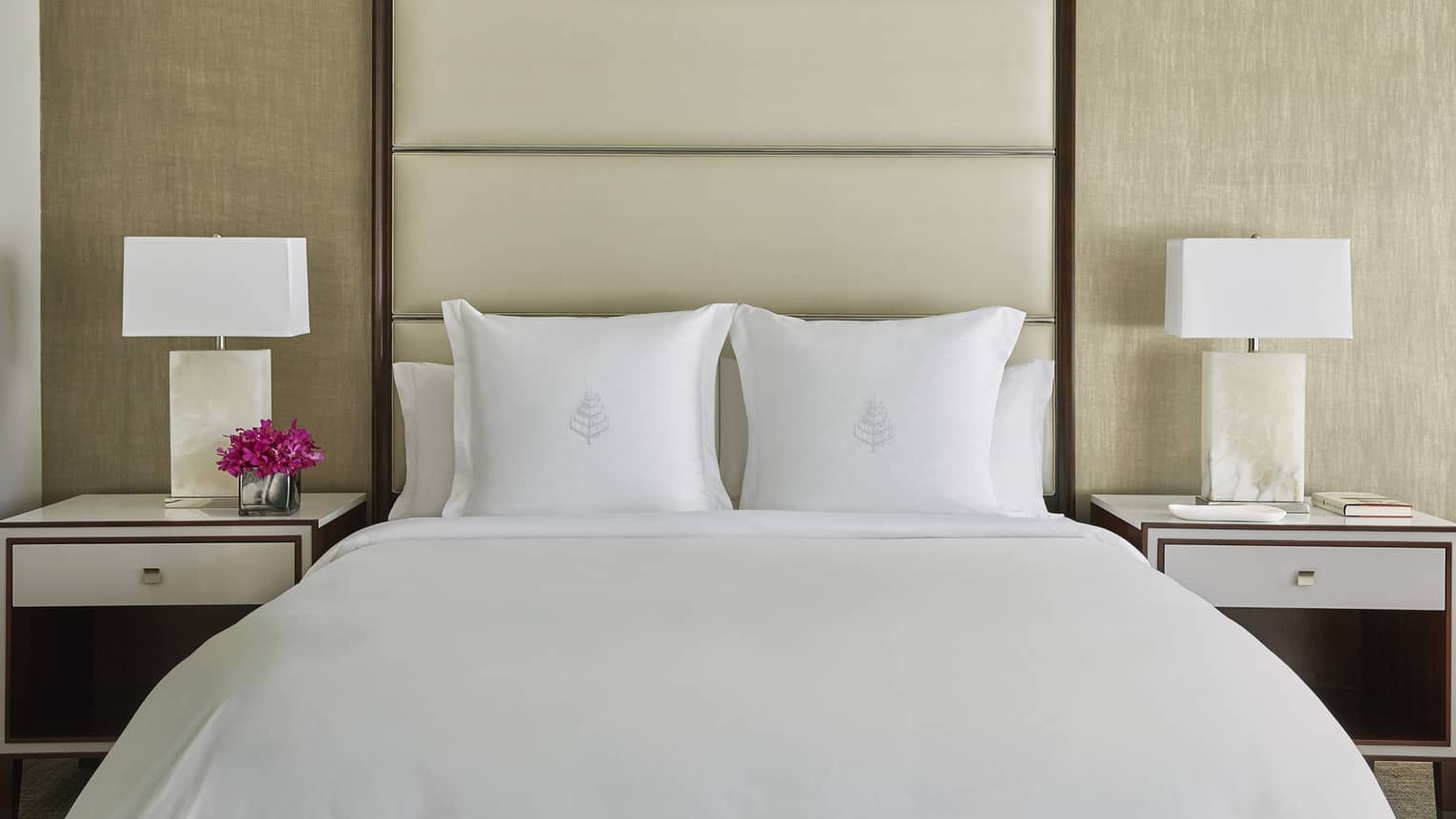 Deluxe Accessible Room head-on view of bed with white linens, tall padded beige headboard, nightstands with lamps