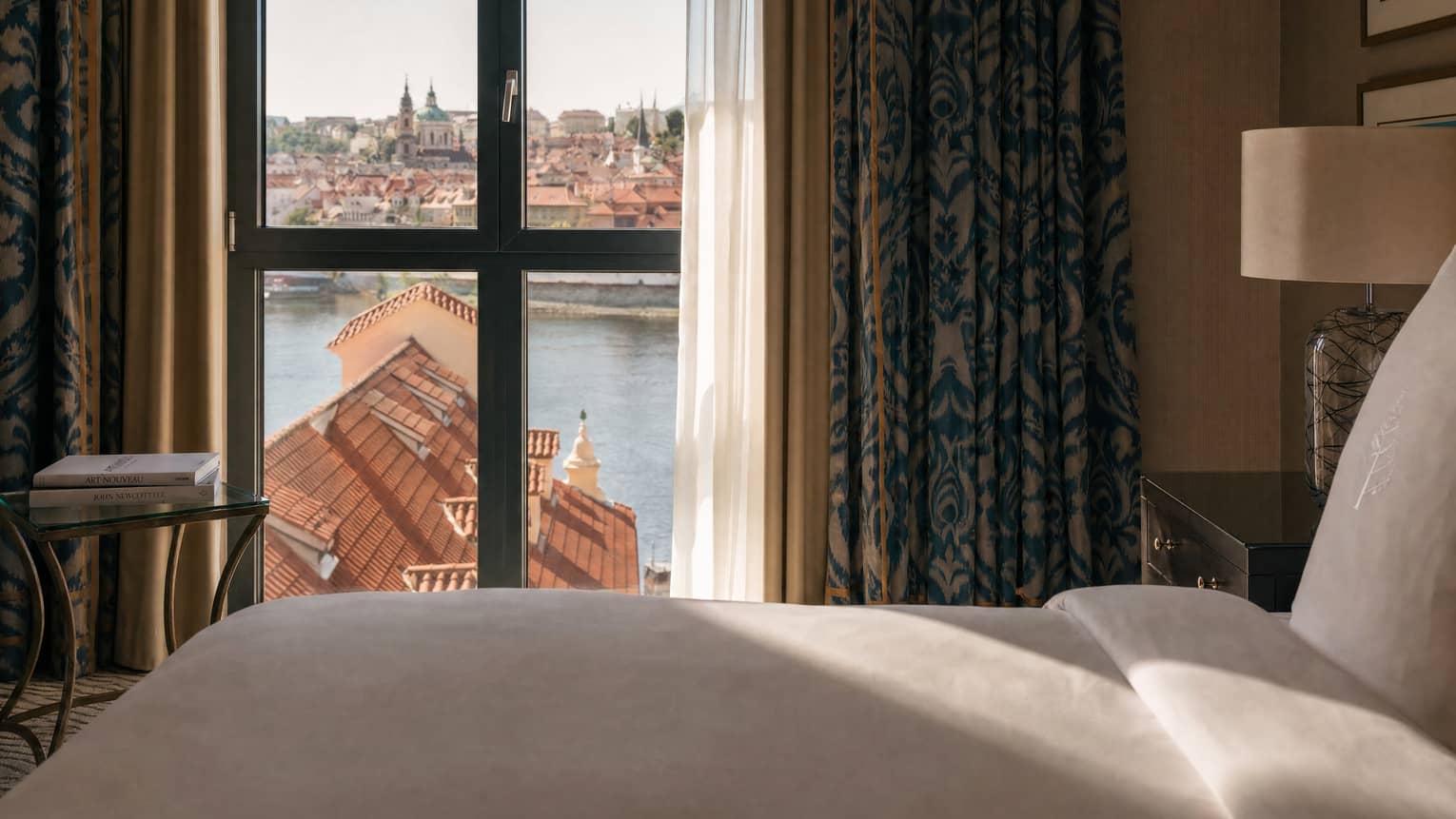 Luxury hotel suite with iconic Prague river view through the window by the bed