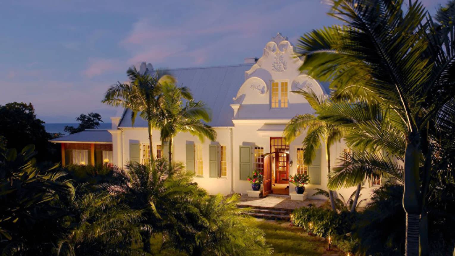 Exterior of a private villa at dusk, with uplighting at the front entrance, at Four Seasons Resort and Residences Nevis