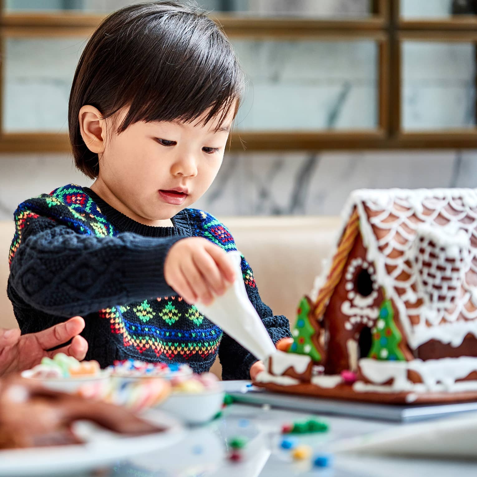 A mother and child make gingerbread houses together