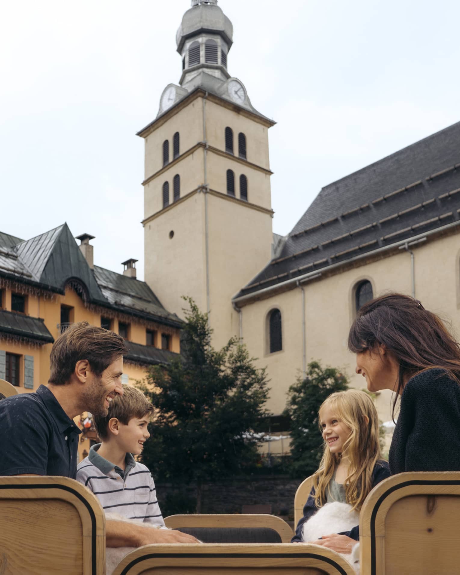 Family of four sitting in a horse-drawn carriage with historic building in background