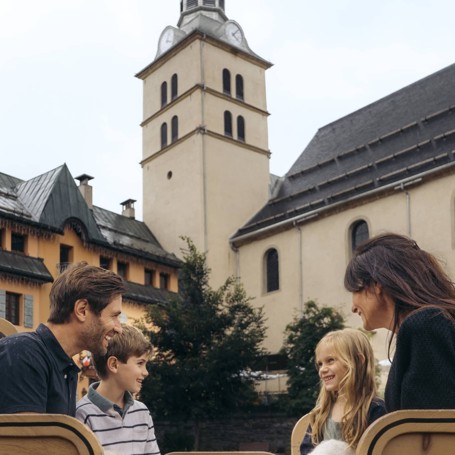 Family of four sitting in a horse-drawn carriage with historic building in background