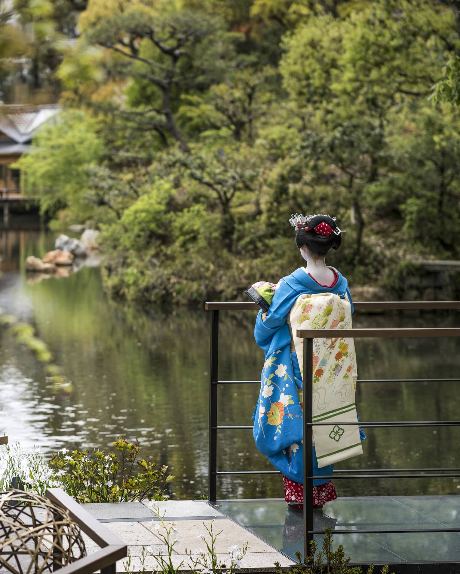 A woman in blue kimono gazing over the garden at Four Seasons Hotel Kyoto, a renowned luxury hotel in Kyoto.