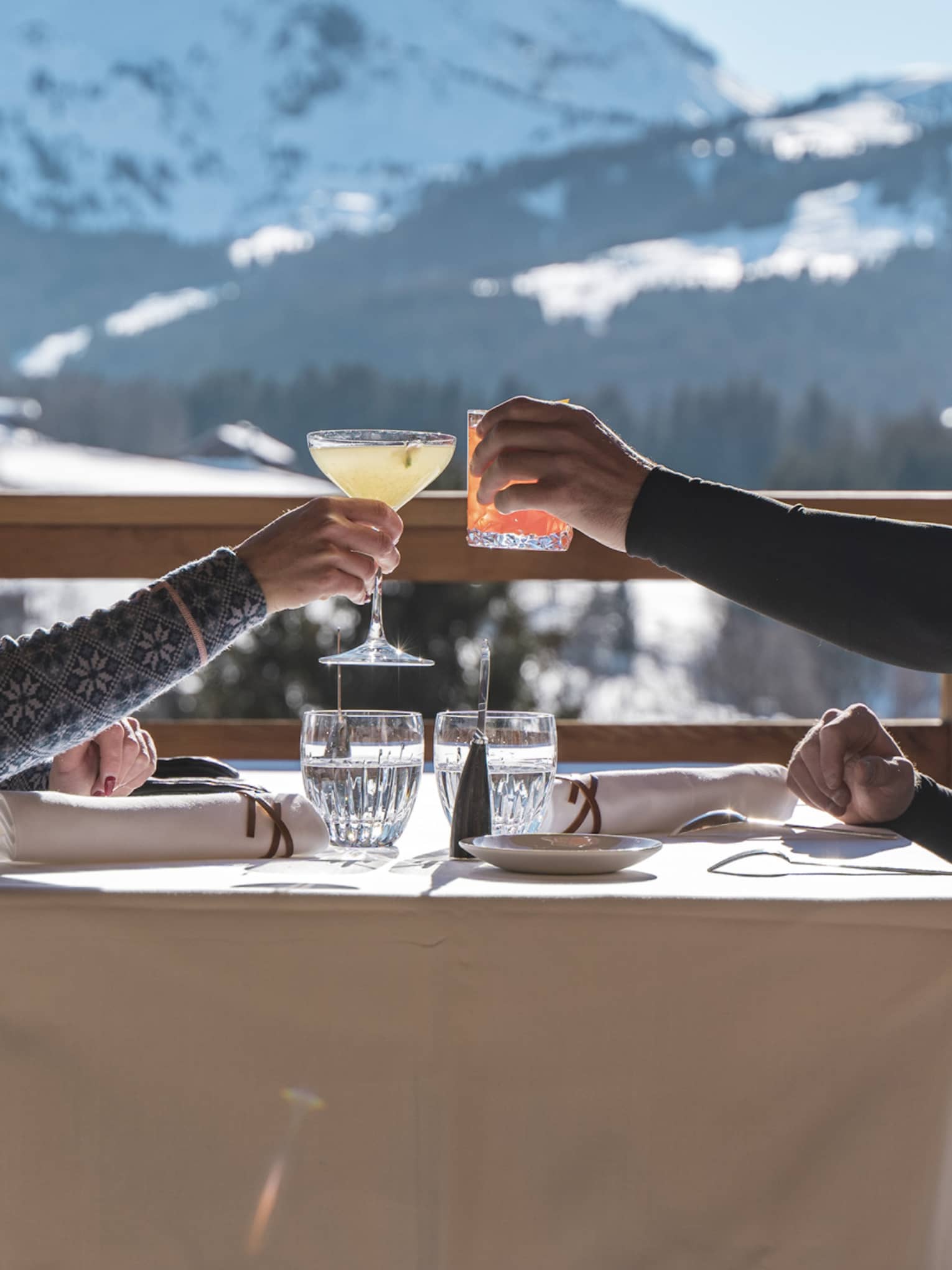 Two people drinking on a patio outside with snowy mountains in the distance