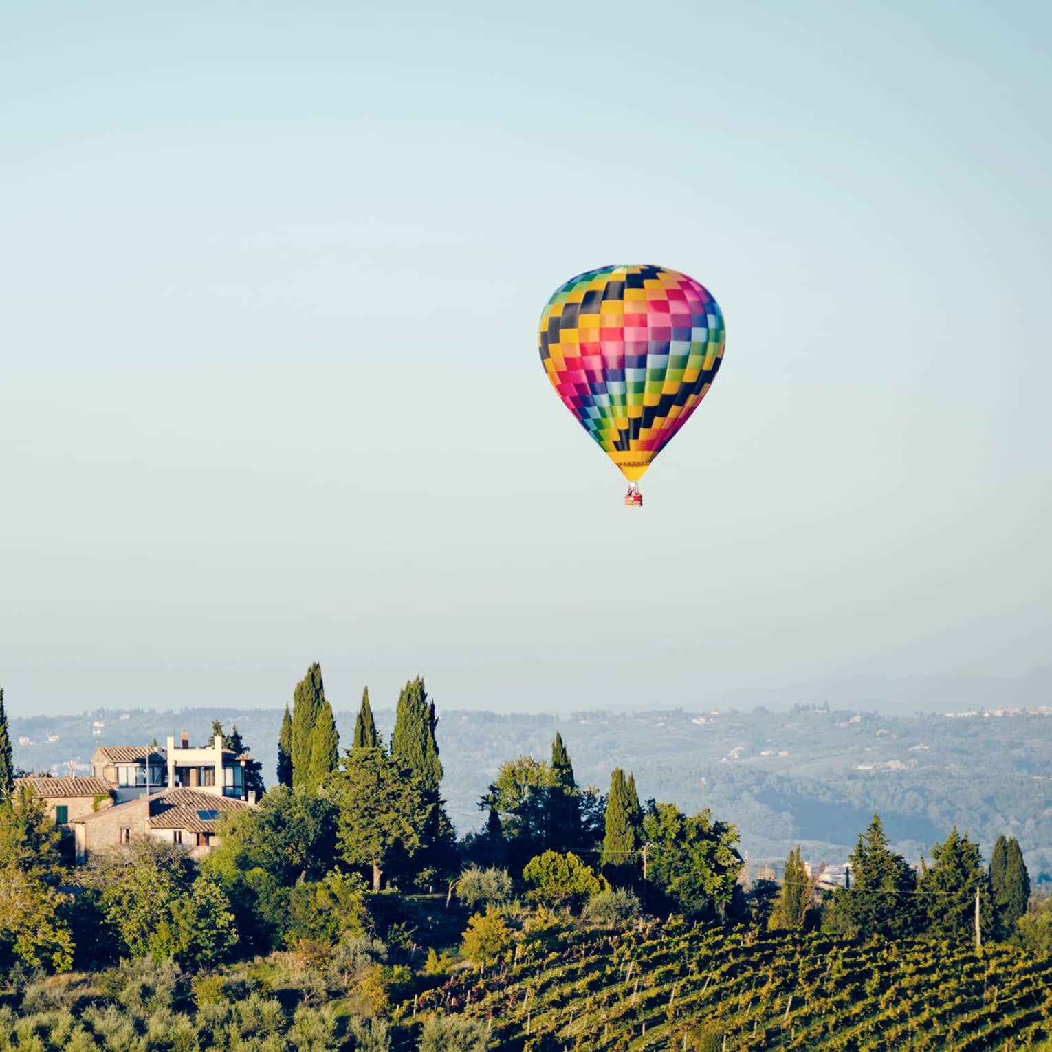 A colorful hot air balloon hovering over a vineyard in Florence