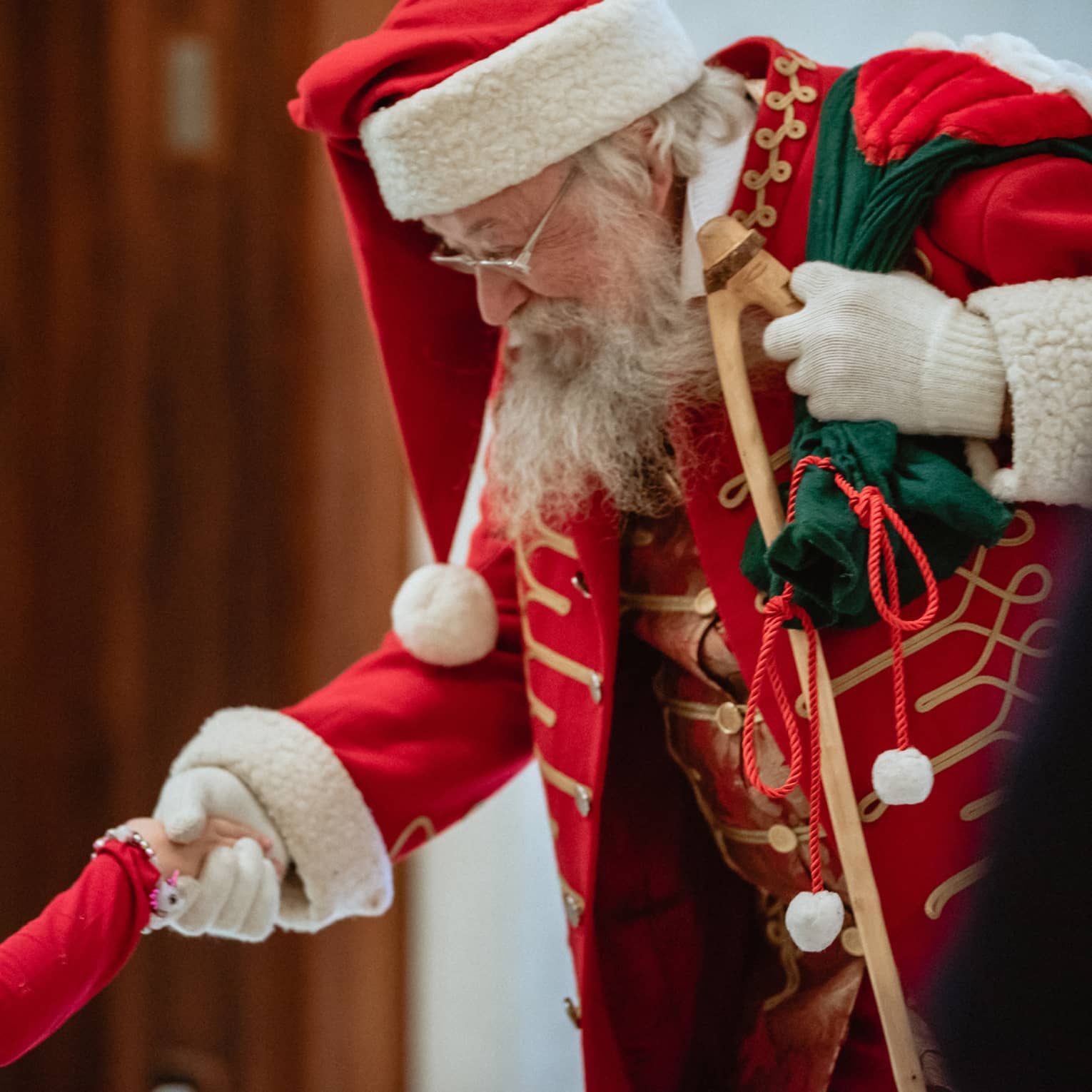 A man dressed as Santa Claus shakes little girl's hand