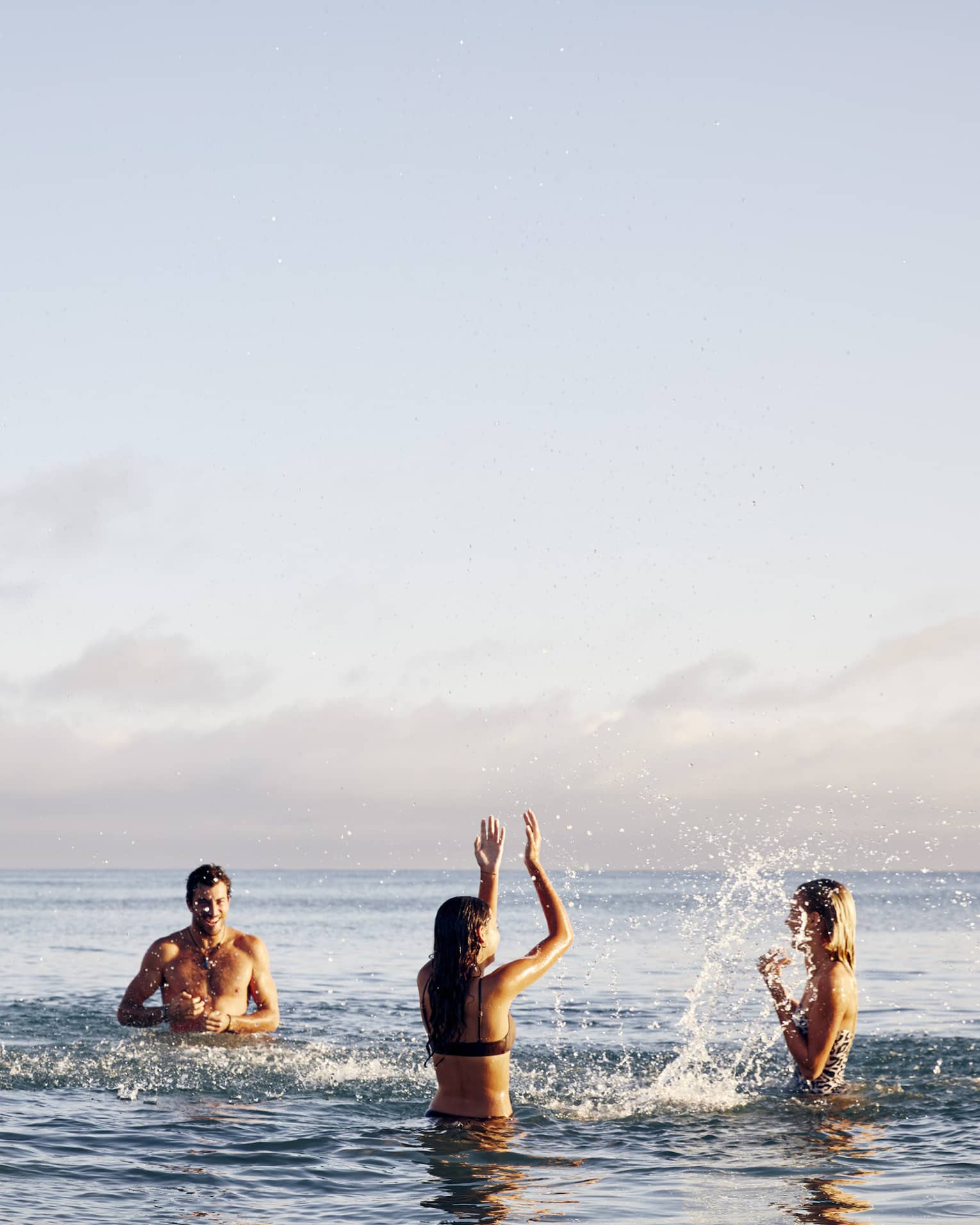 A group of fit men and women relaxing and playing in the ocean.