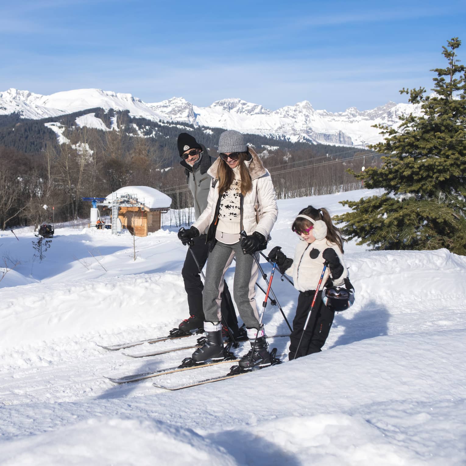 A father, mother and daughter on skis standing on snow.