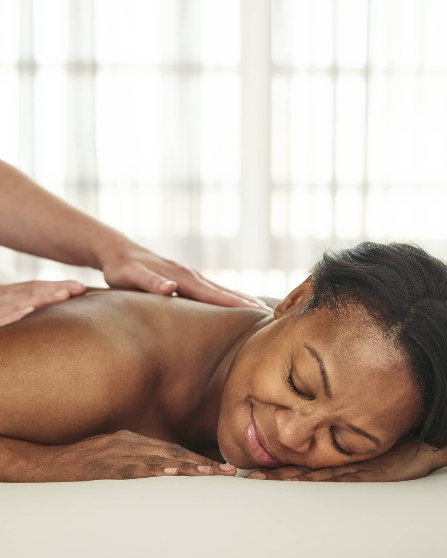A person getting a massage in a well lit treatment room.
