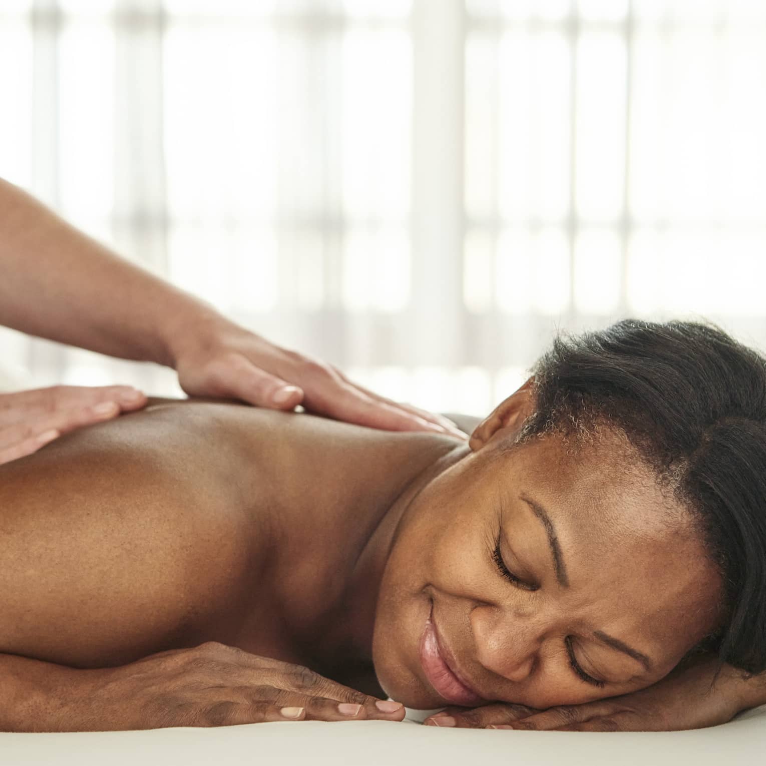 A person getting a massage in a well lit treatment room.