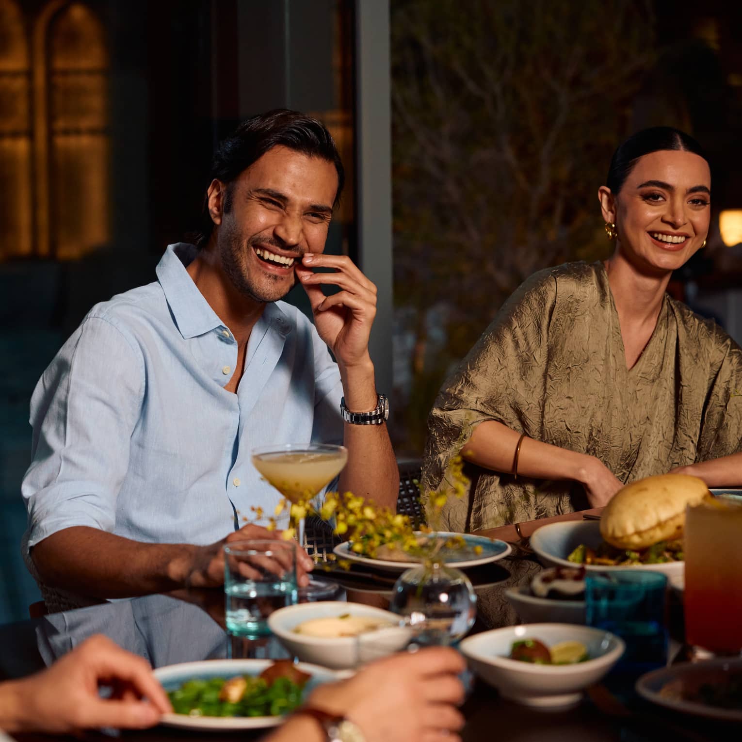 Three people sit smiling around a dining table