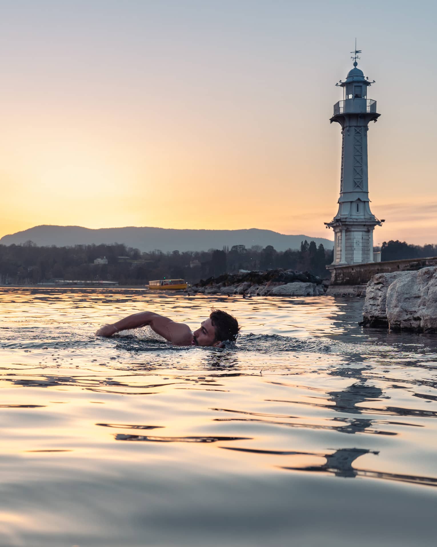 Person swimming in Lake Geneva at sunset
