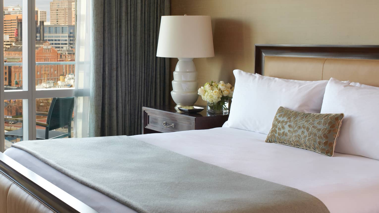Admiral Suite close-up of bed with folded mint green blanket, accent pillow, white lamp, flowers