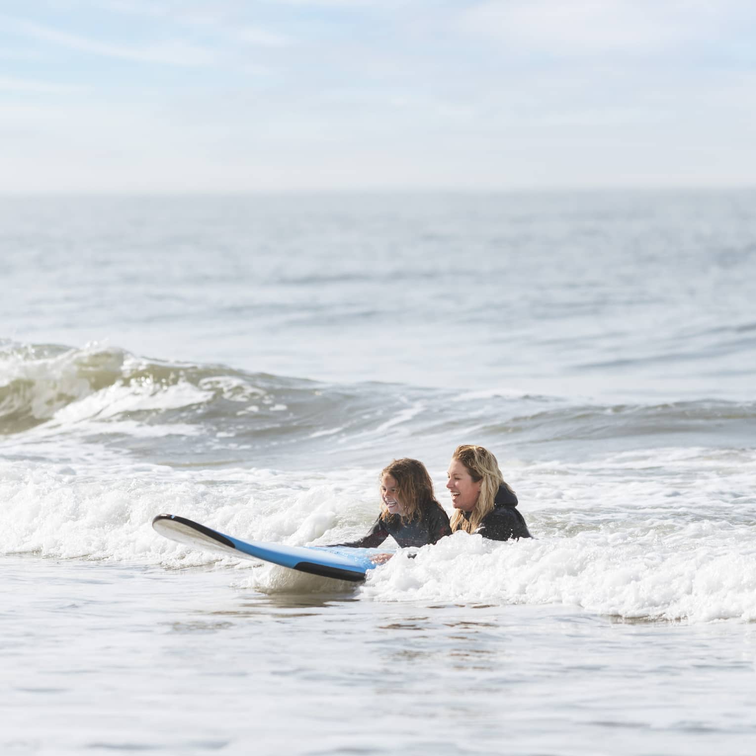 A mother and child practicing surfing at the beach.