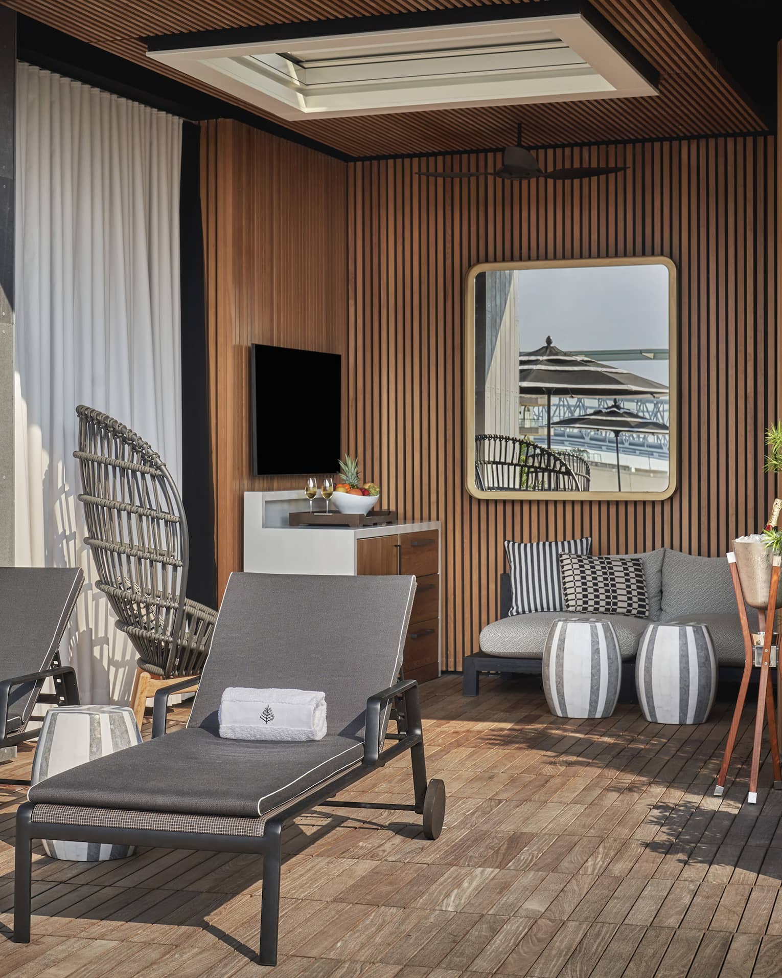 A cabana with two lounge chairs a sofa and plants.