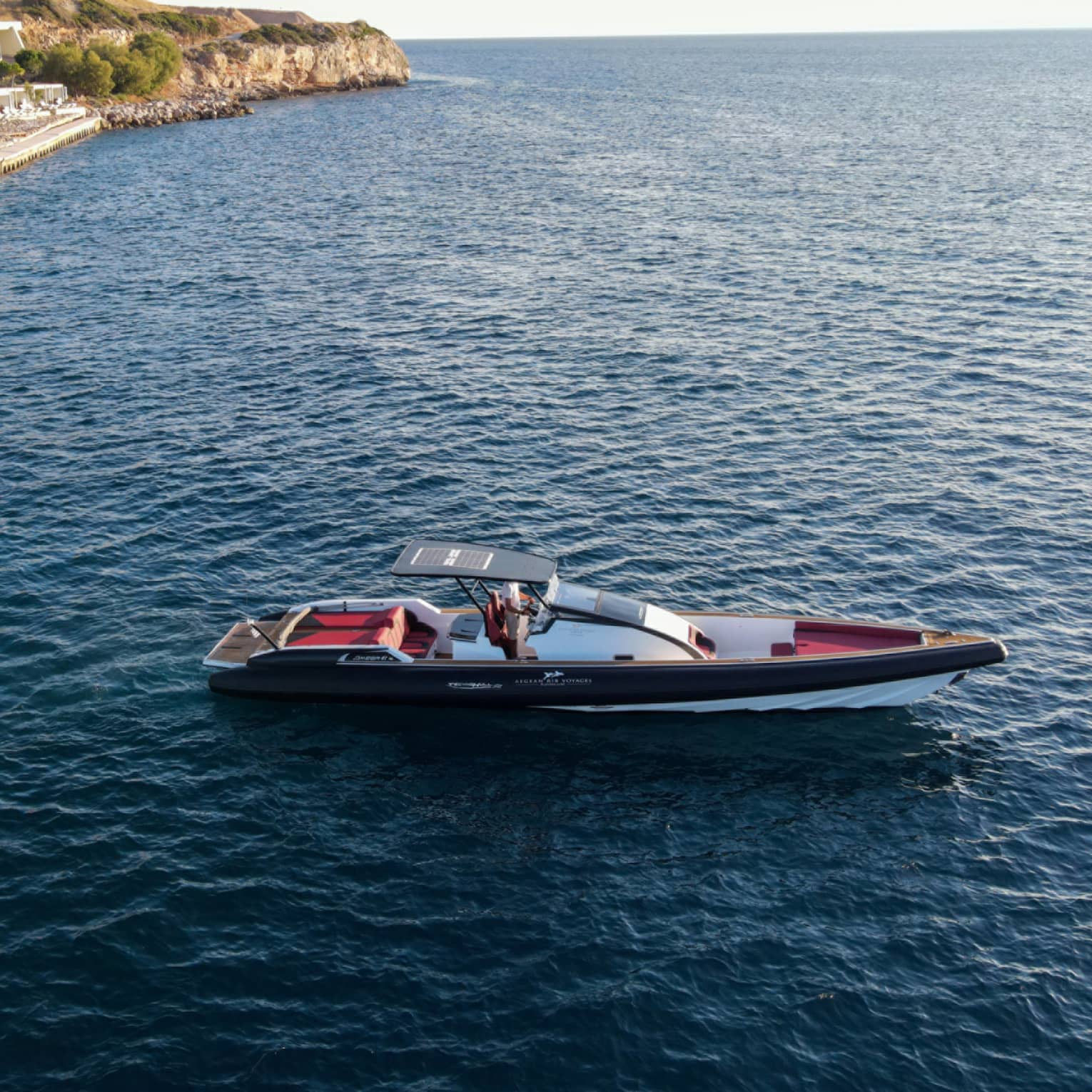 Small Greek-style yacht heading out toward open water from Astir Palace Hotel dock.