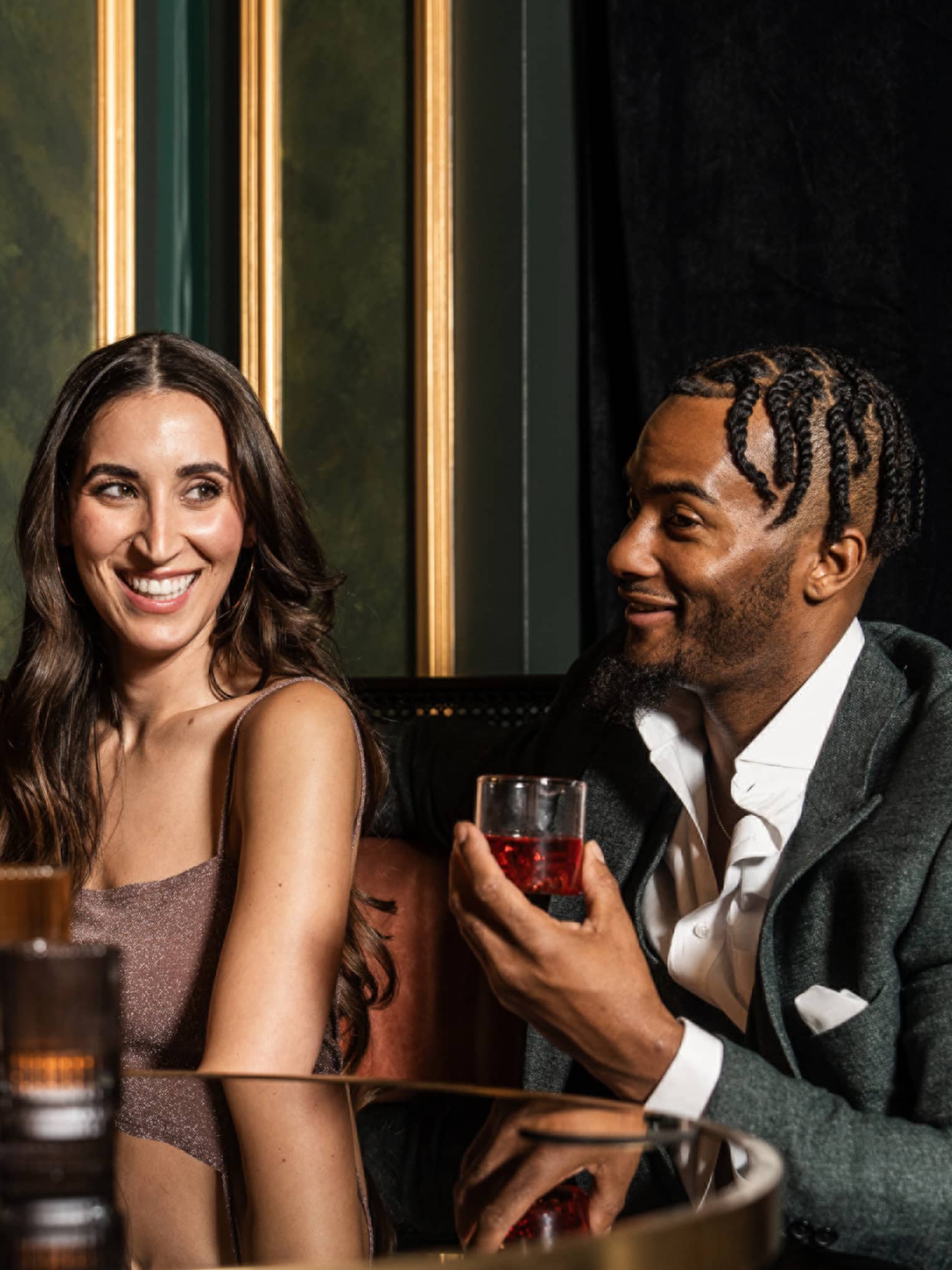 A man and woman drinking at a booth in a dim restaurant.