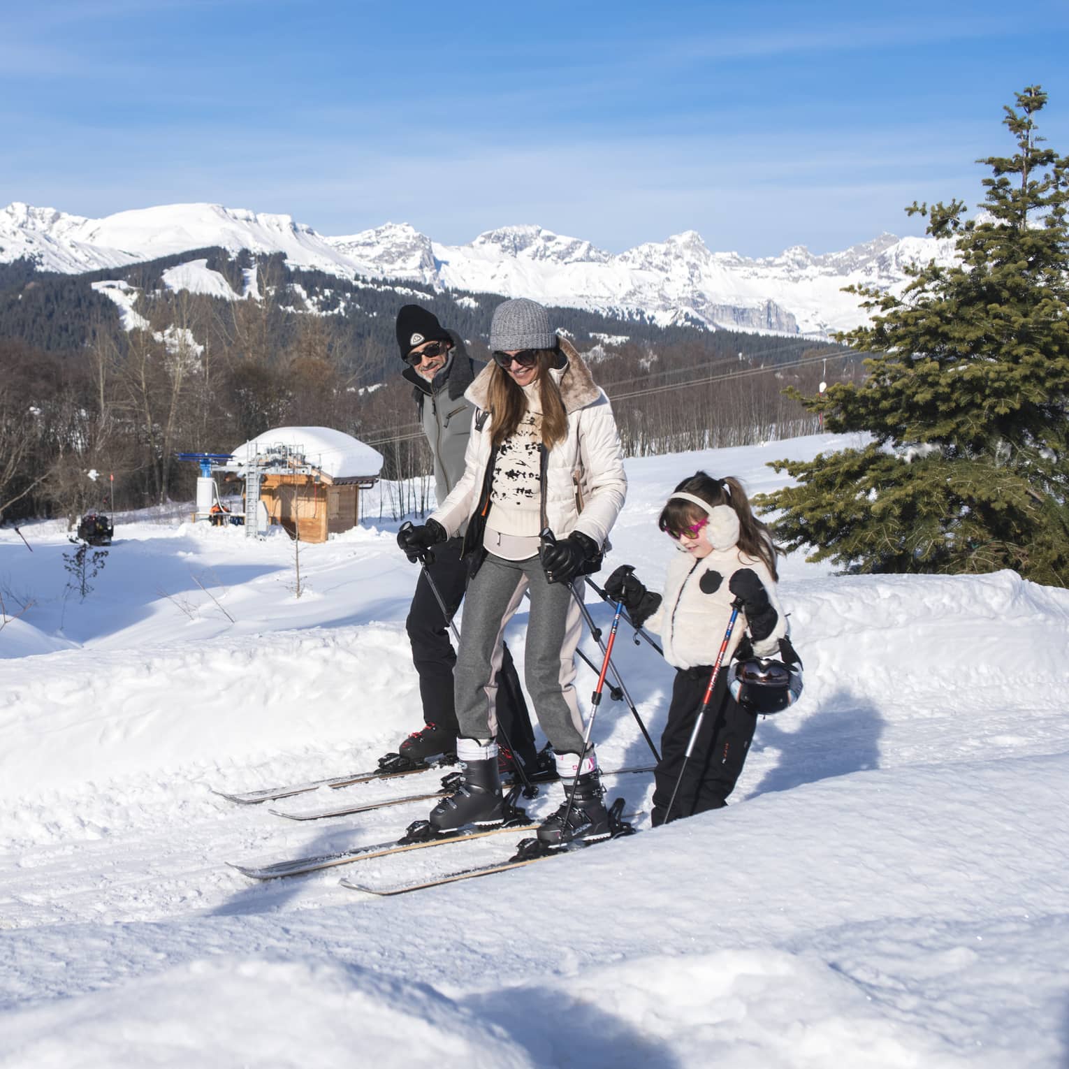 A father, mother and daughter on skis standing on snow.