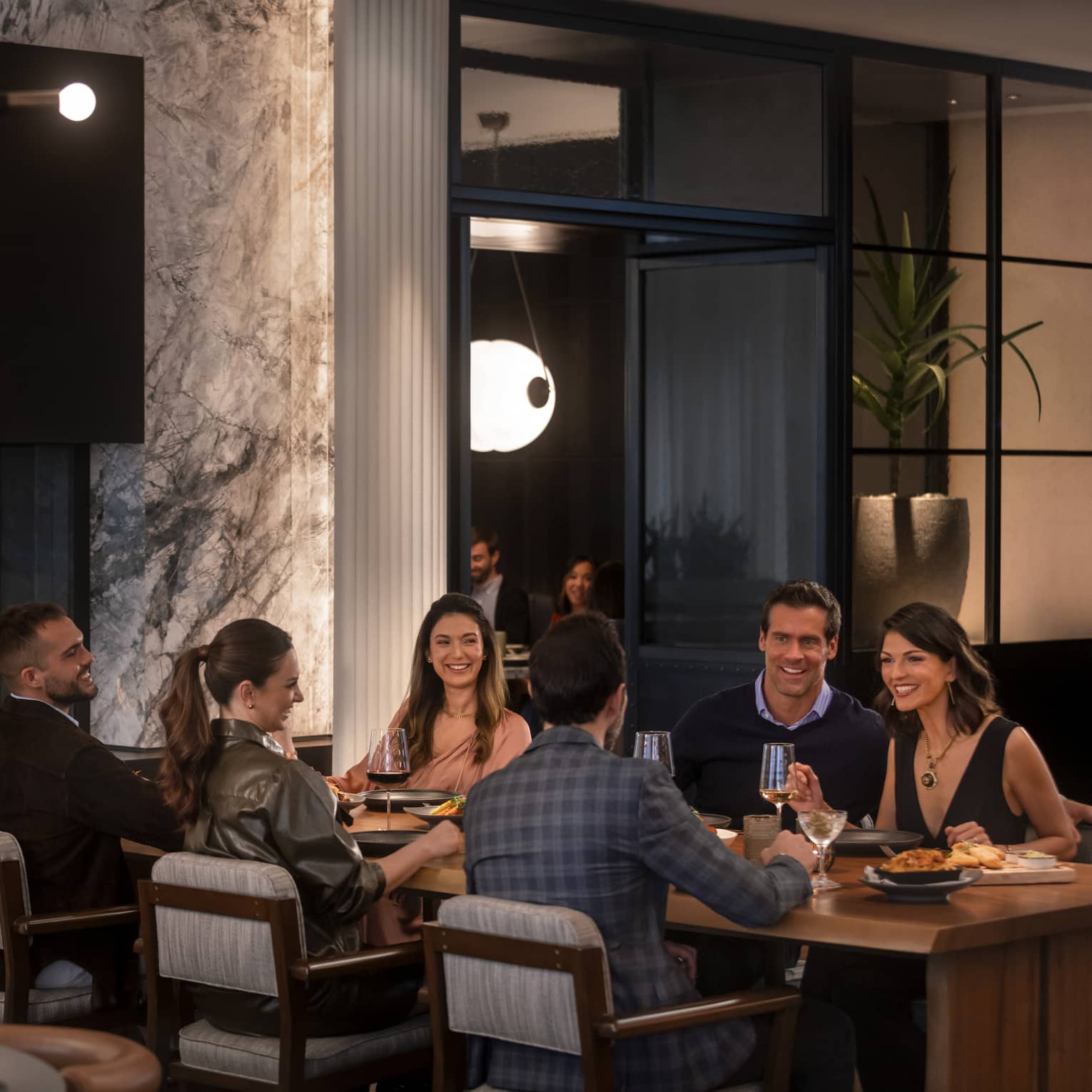 A group of people sitting at a large table in a dimly lit restuarant.