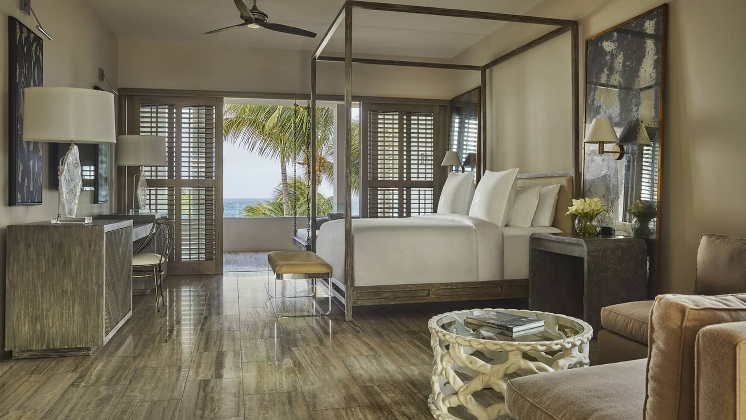 Elegant bedroom with four-poster bed, tropical décor and balcony view of palm trees and ocean