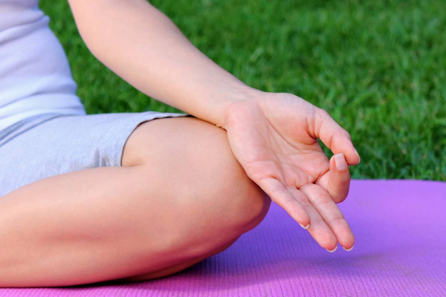 Side of hand, leg in cross legged meditation pose on yoga mat