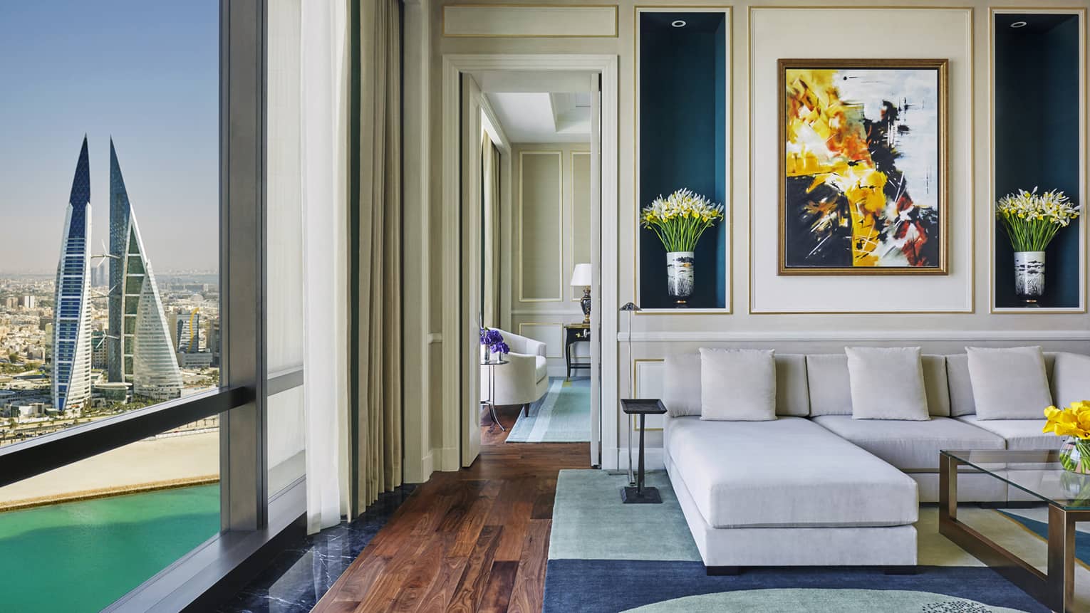 Hotel room sofa beside floor-to-ceiling window with view of waterfront, beach, modern towers