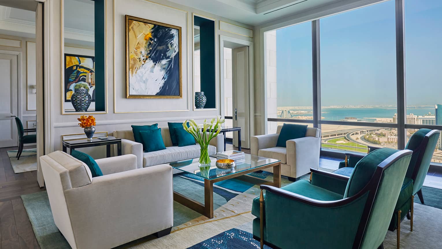 Hotel room living area with beige, green and gold seating area, modern art on wall, sunny windows