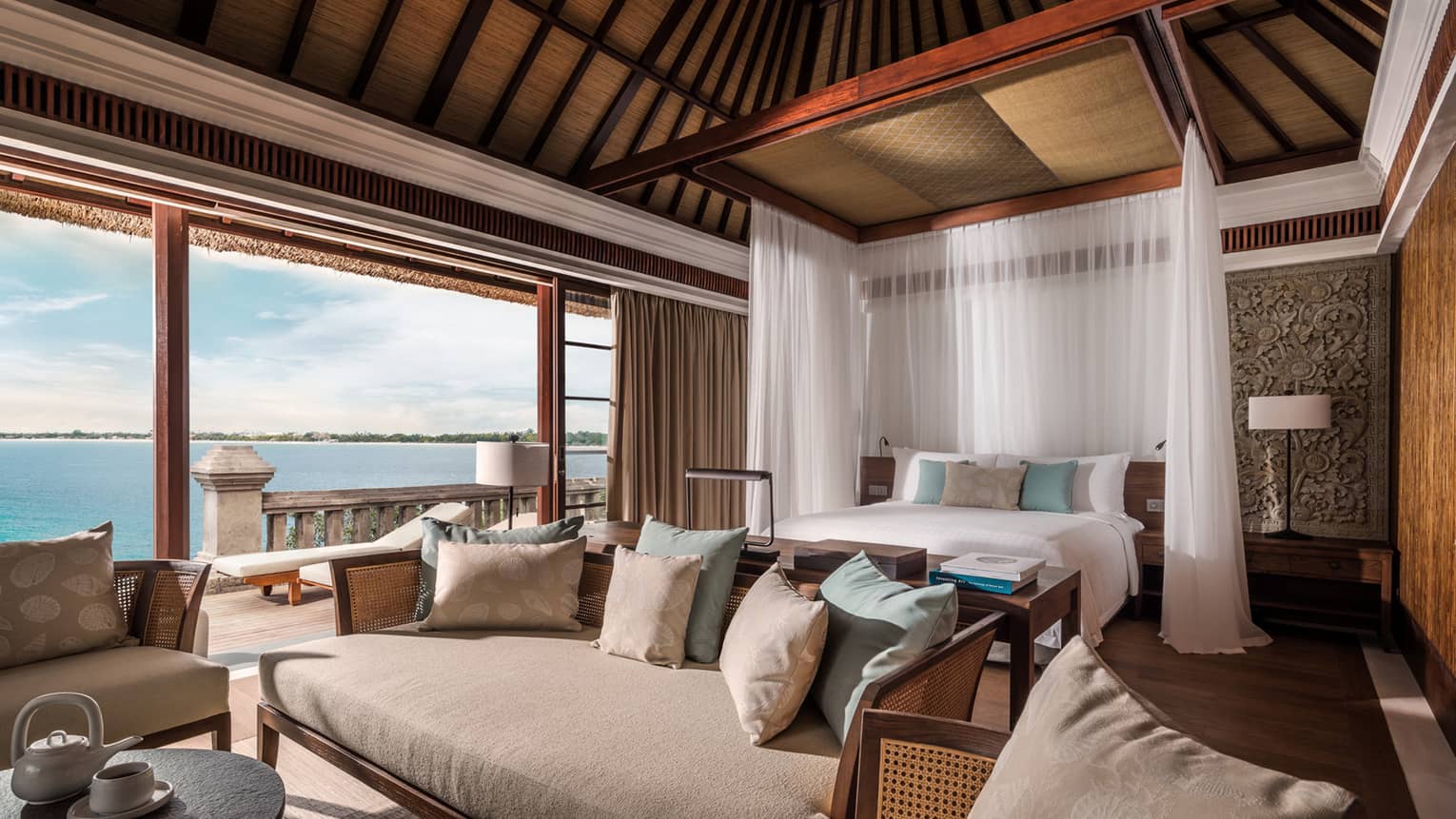 Family Premier Villa large bed with white drapes, sofa seating area, open wall to patio, ocean view