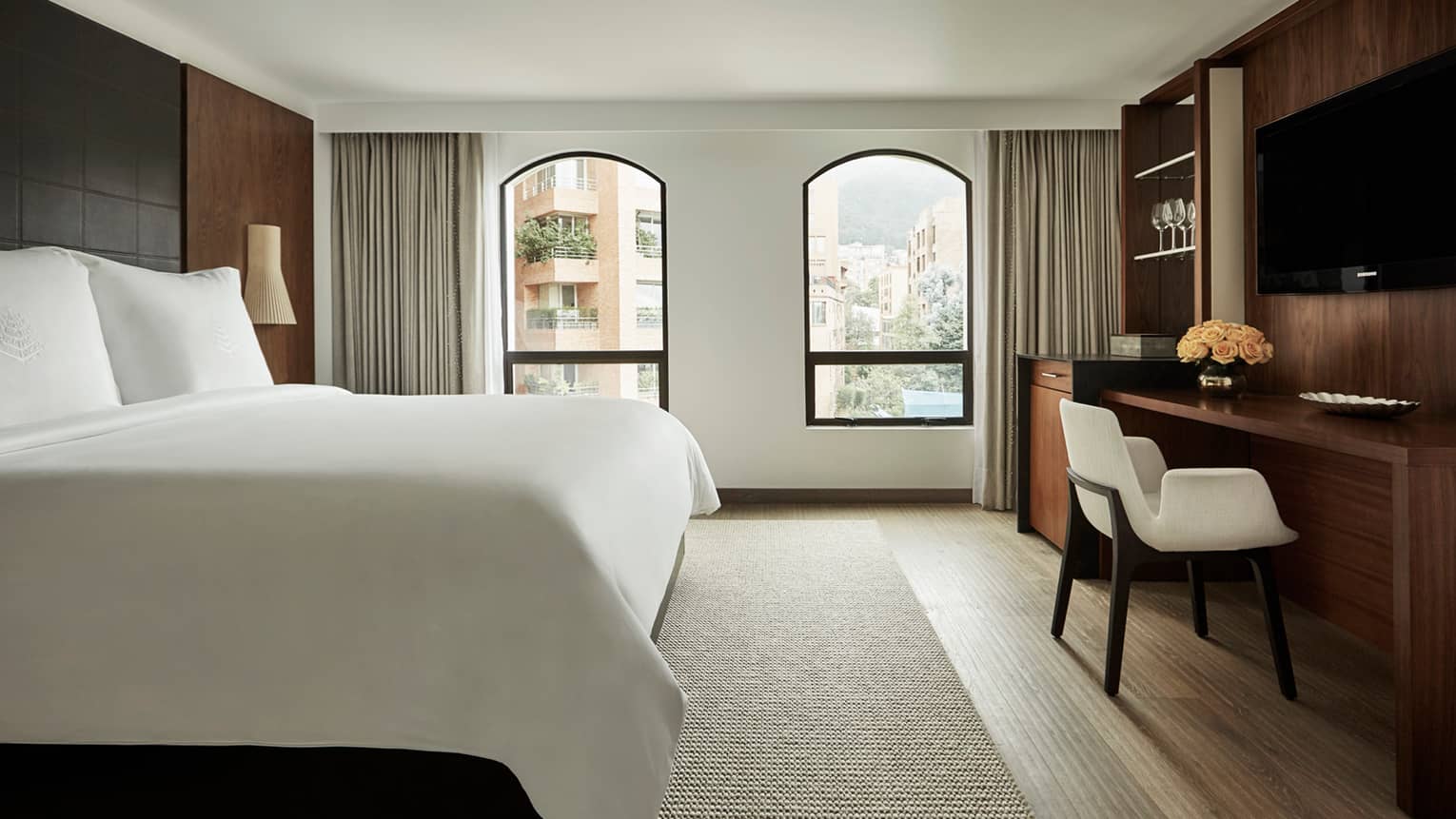 Superior Room bed, two windows with sunny city view, flat-screen TV over wood desk with white chair