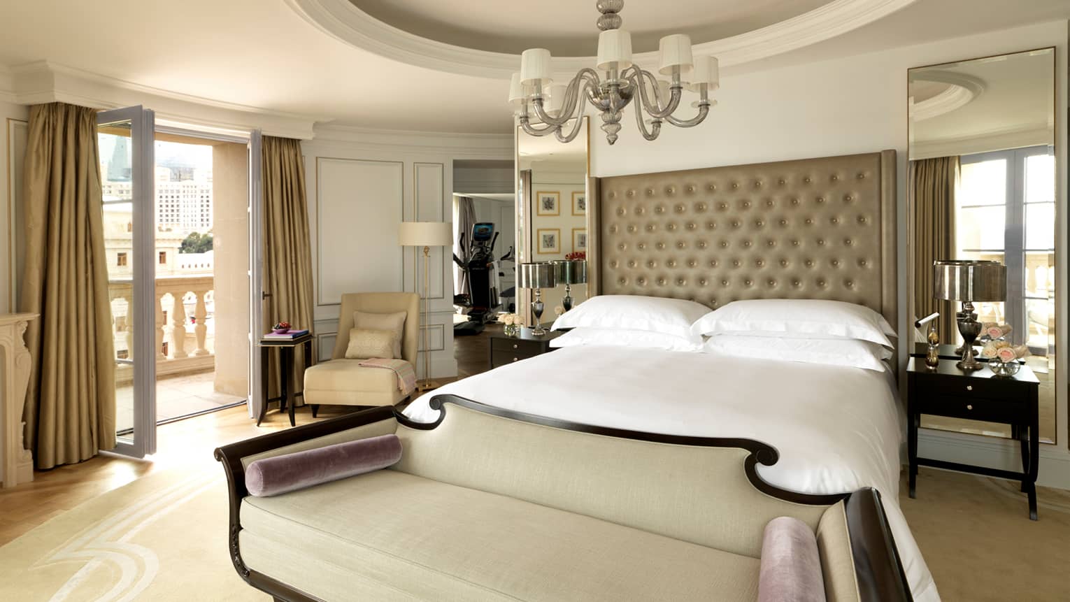 Liman Presidential Suite with Art Deco-style loveseat at foot of white bed under dome ceiling with chandelier, open balcony doors