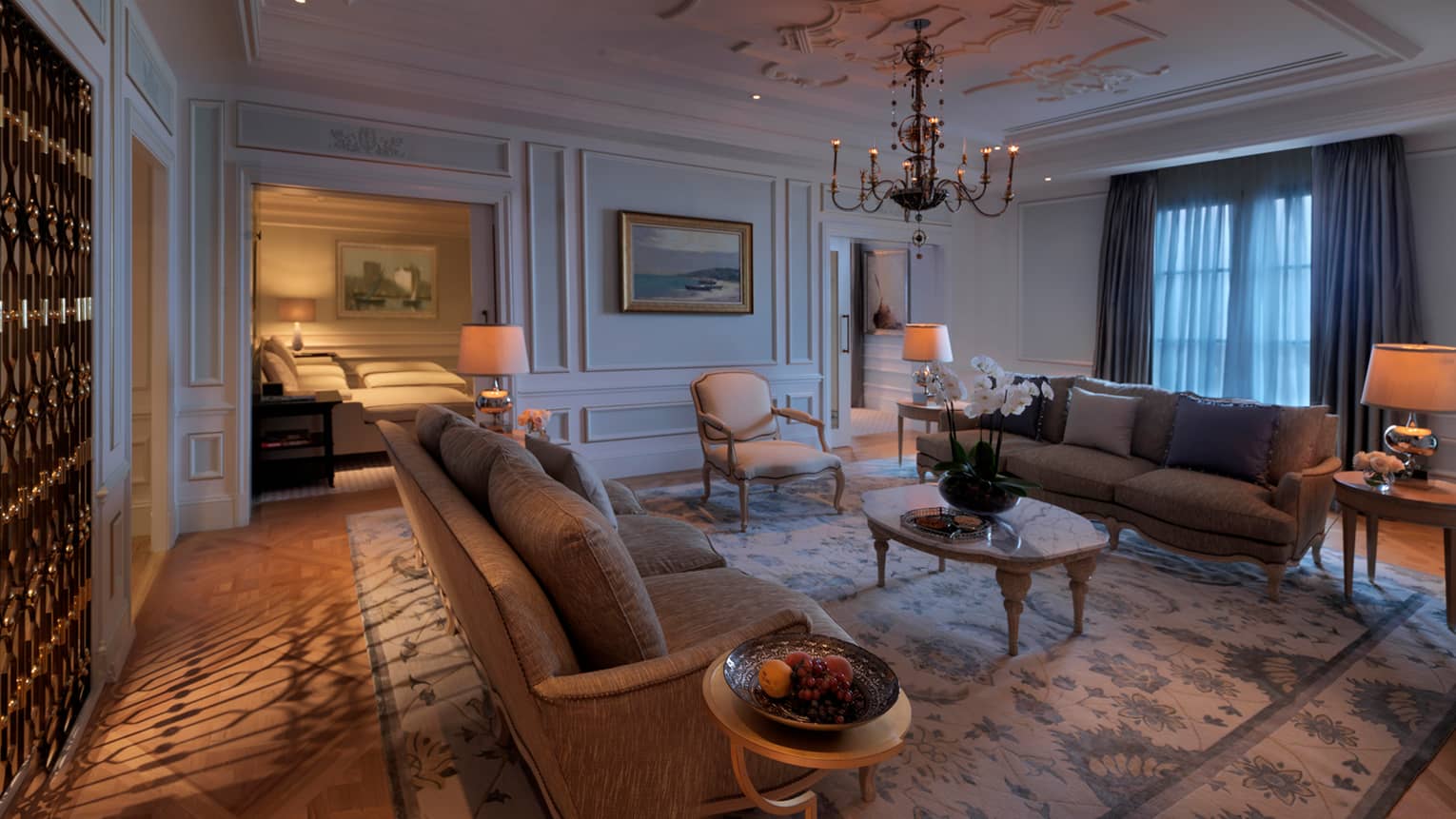 Large, dimly-lit  Khazar Presidential Suite living room, area rug, antique-style chandelier