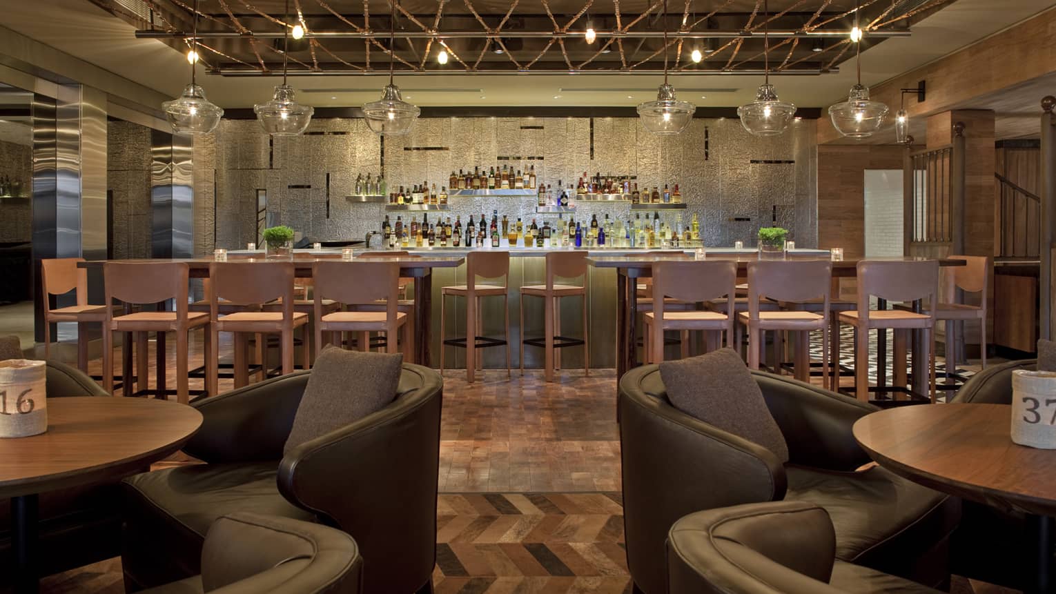Pony Line view between two lounge tables, leather armchairs to bar with high stools, liquor display