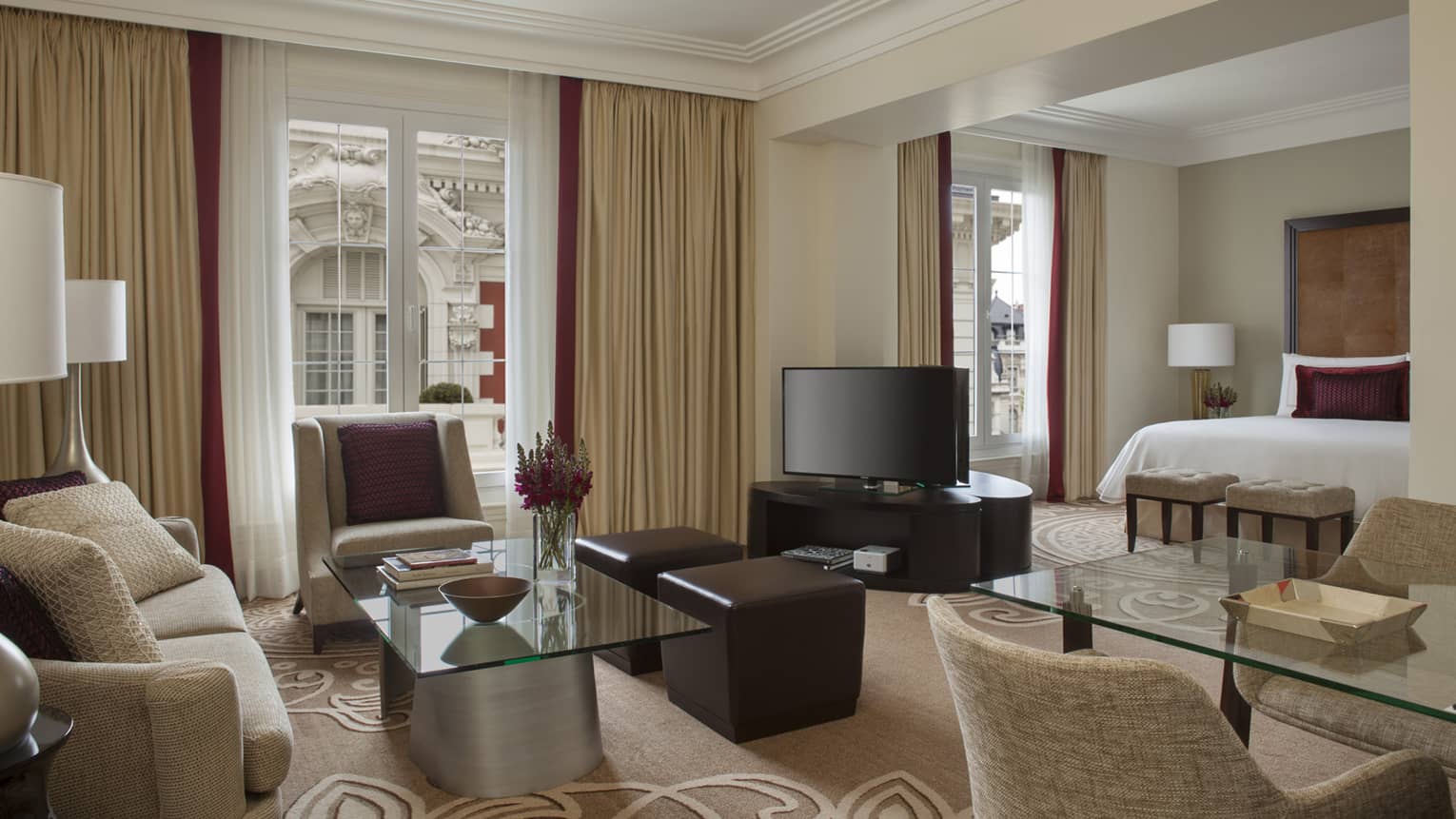 Mansion-View Junior Suite living room with beige loveseat, armchair, glass coffee table and dining table, TV, bed