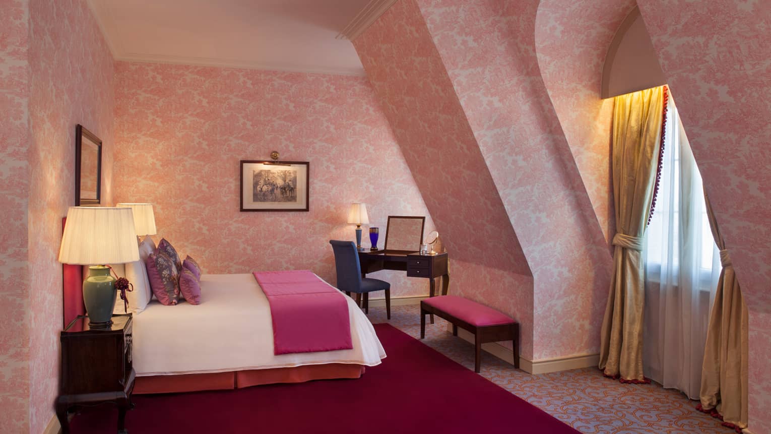 La Mansión Diplomatic Premier Suite with pink-patterned wallpaper on sloped walls, bed, bench and desk