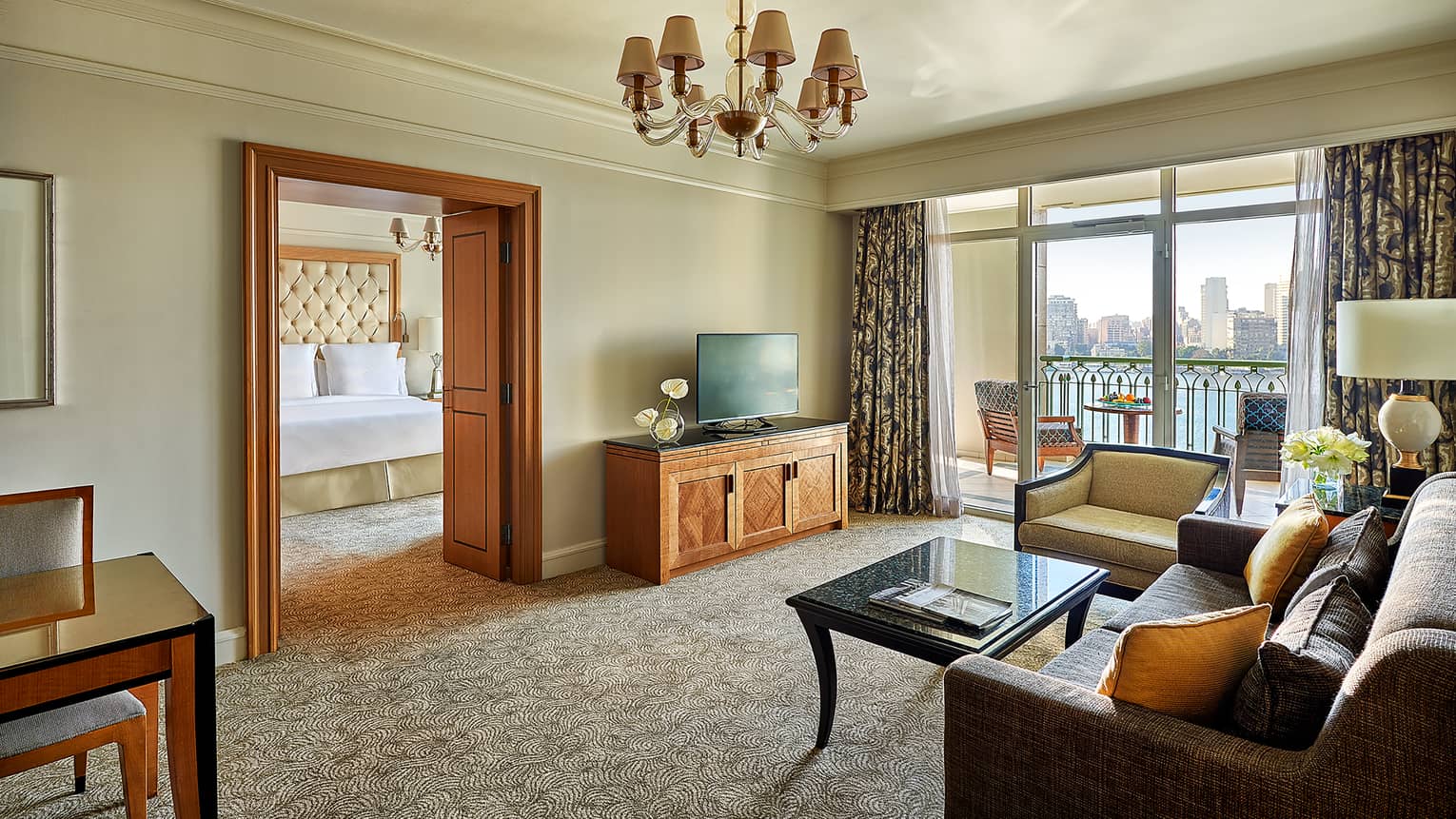 Suite living area with sofa, TV and coffee table, looking into adjoining bedroom at bed