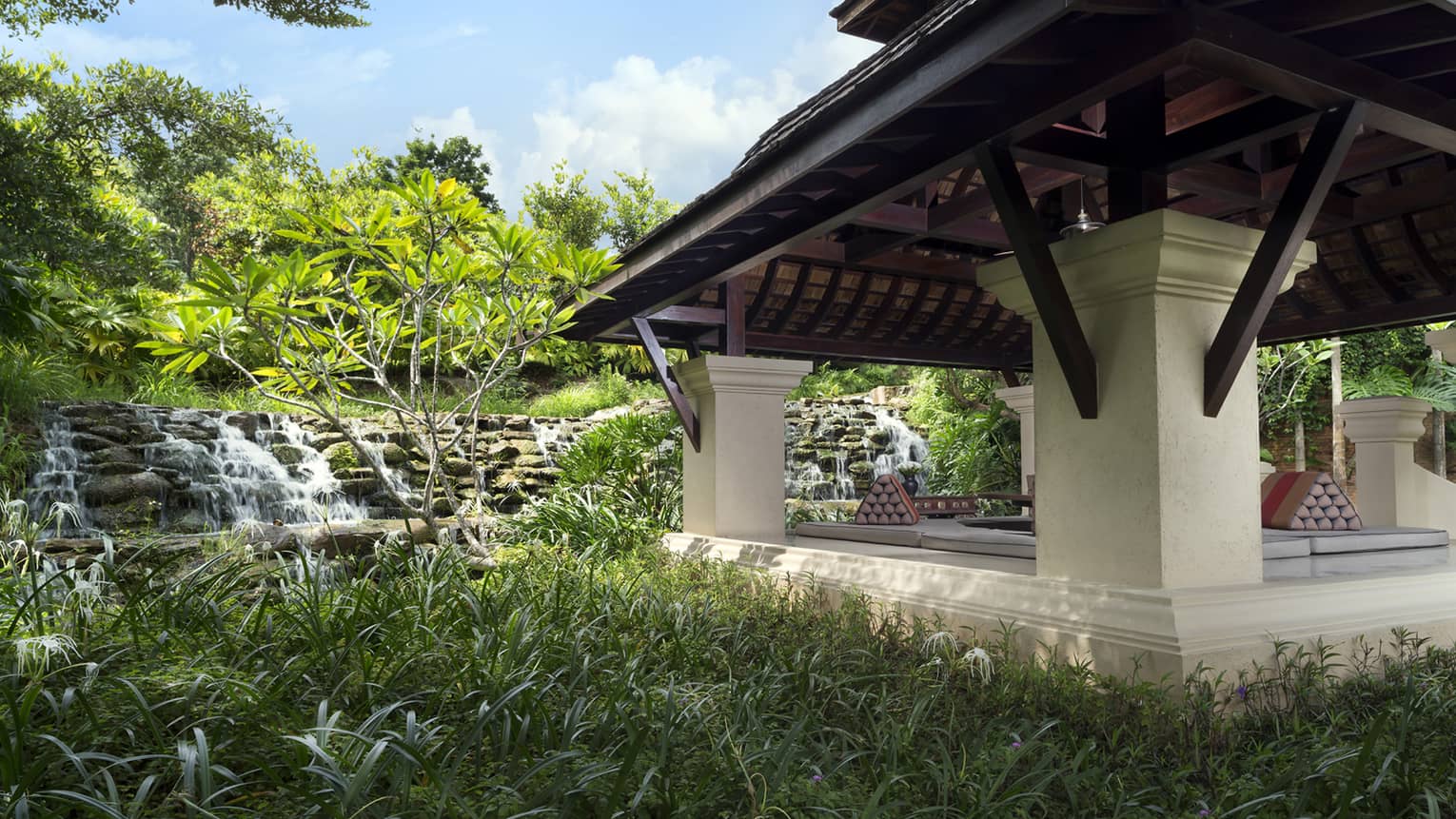 Large pavilion by stone waterfall, tropical gardens 