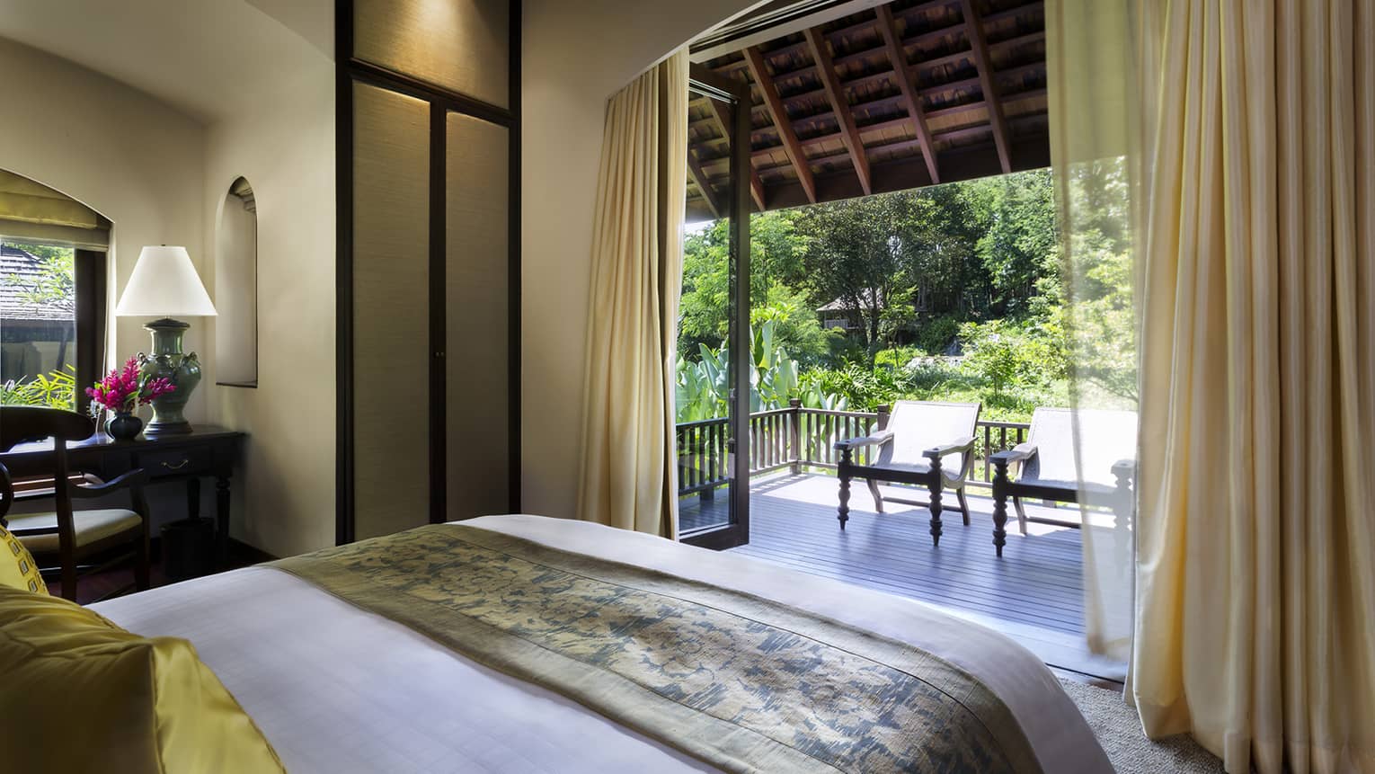 Family Residence bedroom end of bed with folded gold blanket in front of open patio doors, curtains