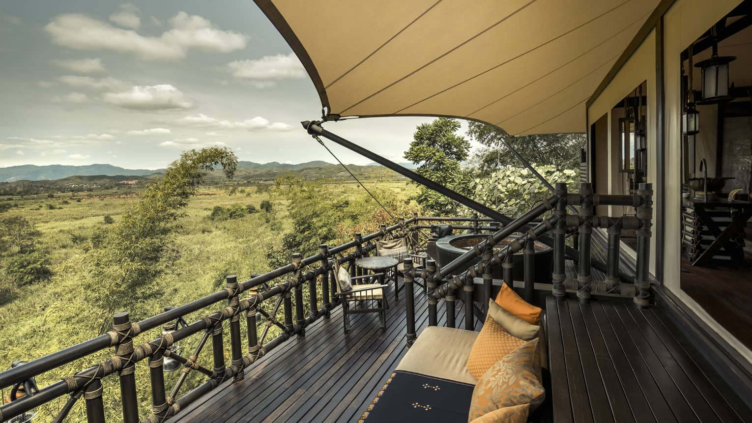 View from balcony of luxury tent with breathtaking scenery, lush greenery and a clear blue sky