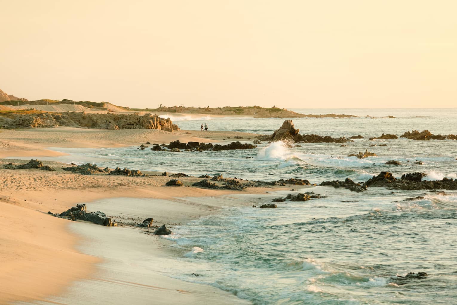 waves breaking on rocks and crashing on a sandy beach