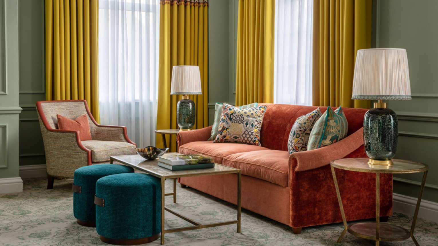 Guest room with red couch, tan accent chair, coffee table and matching end tables, twin windows with yellow drapes