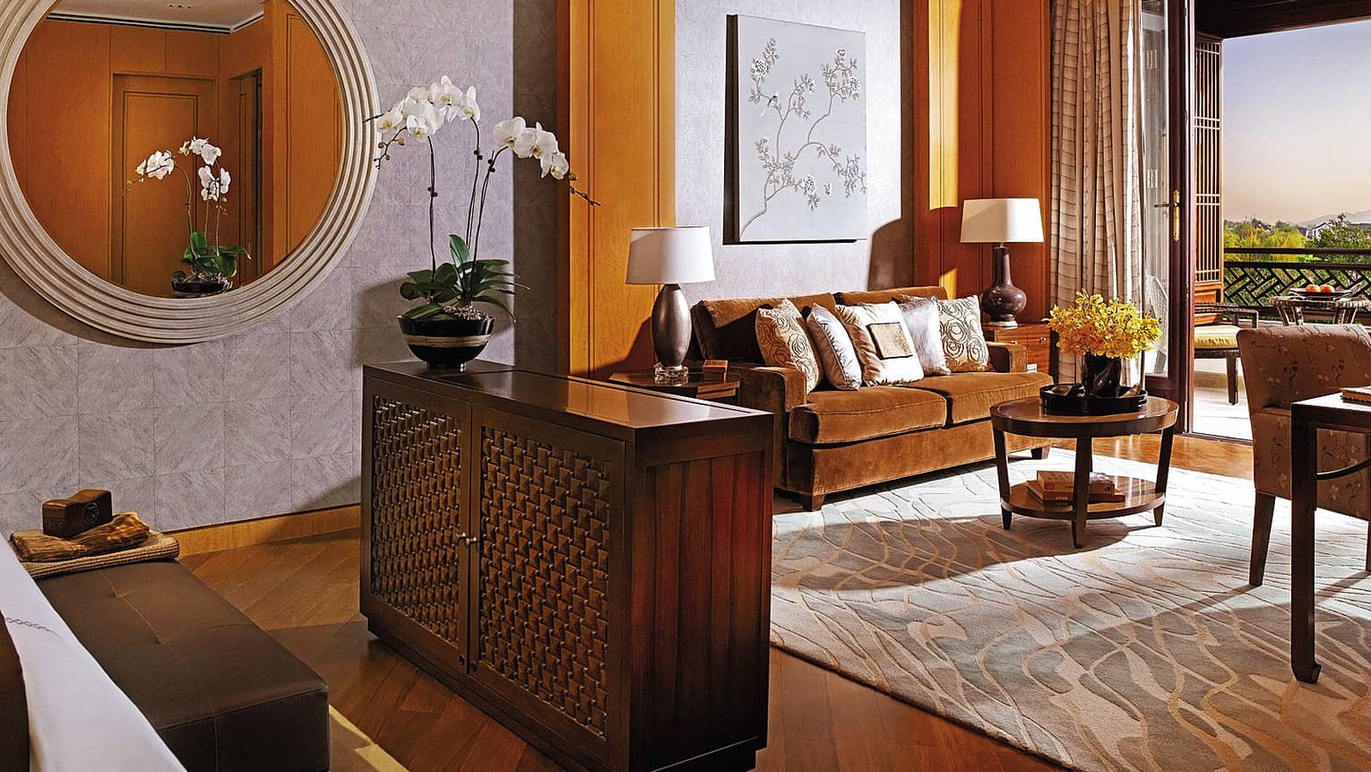 Premier Room large round mirror on wall by wood dresser, orange velvet loveseat, open wall
