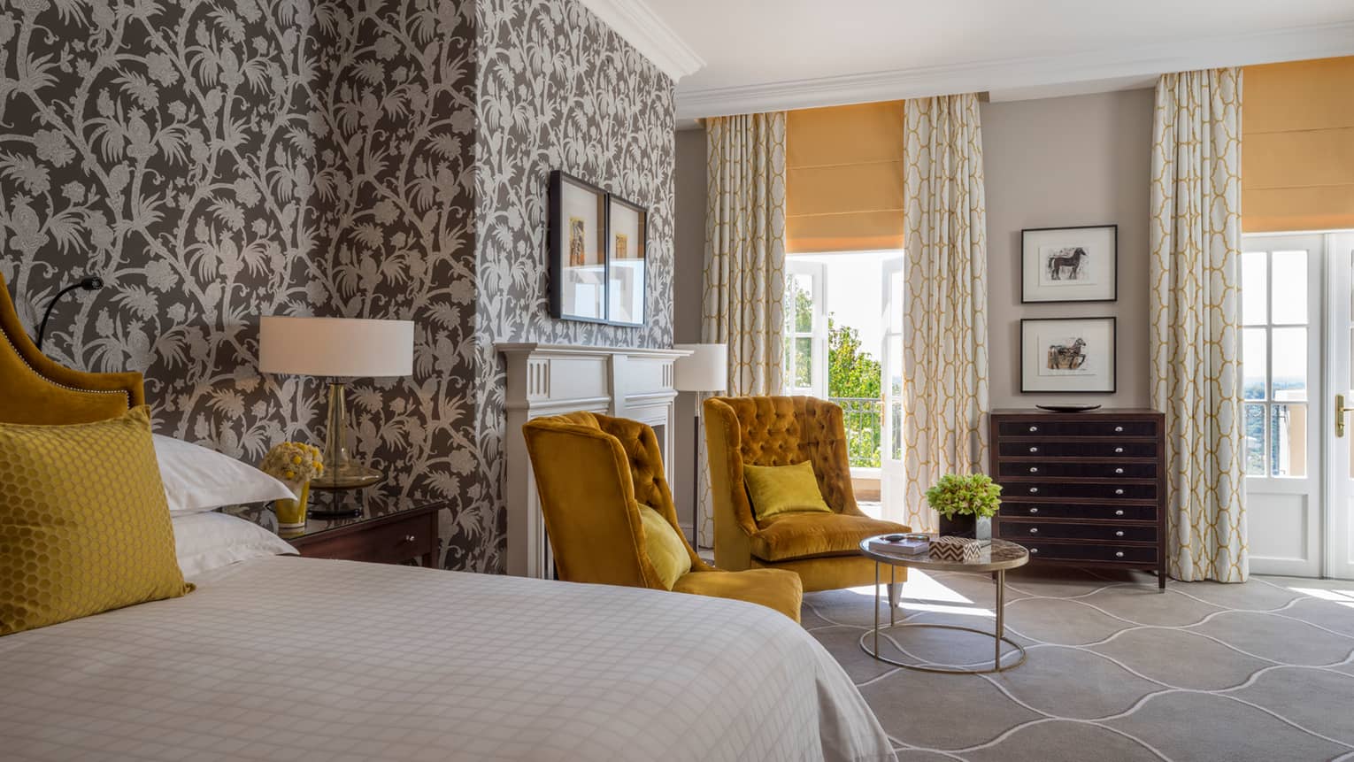 Royal Suite bed, two gold tufted armchairs around small glass table, tropical wallpaper 