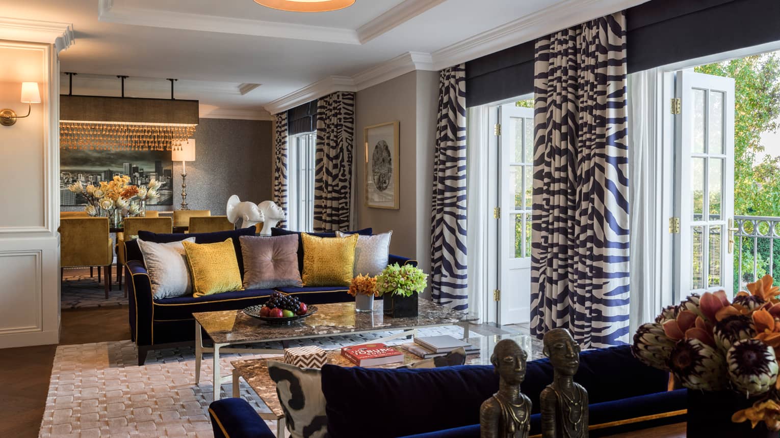 Royal Suite sitting area, two blue sofas with yellow, grey pillows, open patio doors with Zebra print curtains