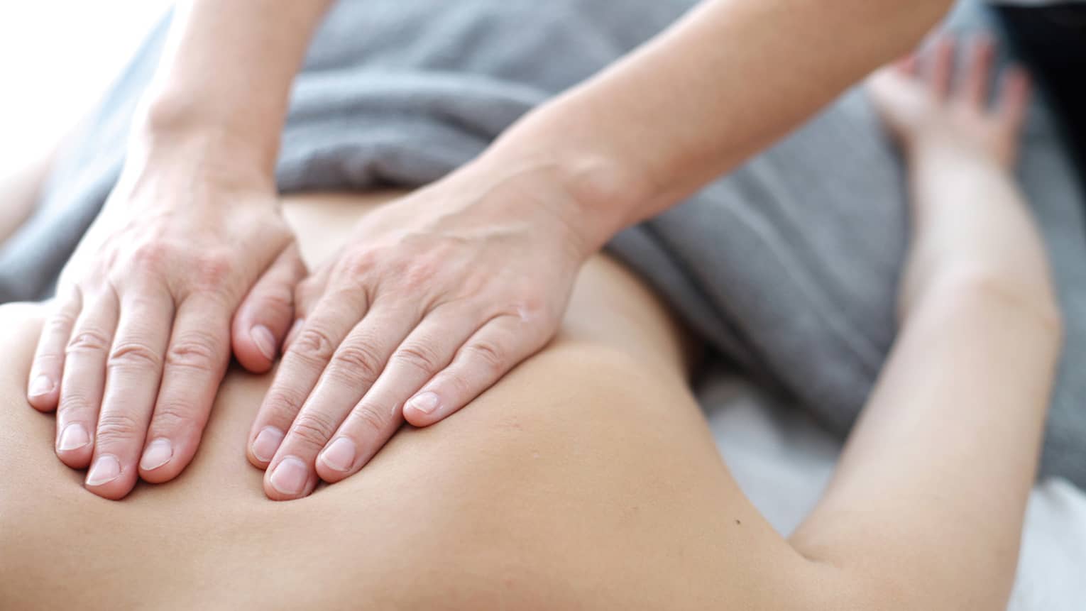 Hands massaging bare shoulders, back