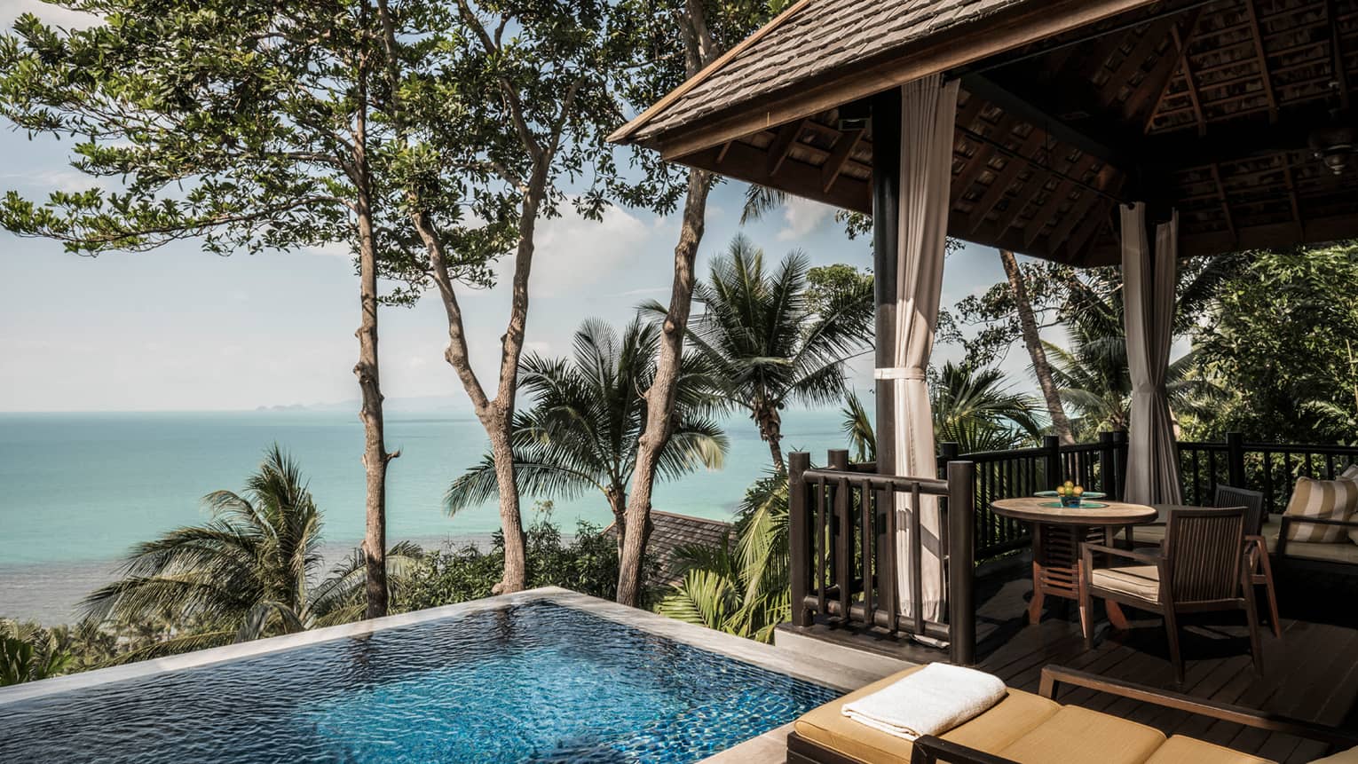 Premier One-Bedroom Pool Villa patio with chairs, table by plunge swimming pool with ocean views