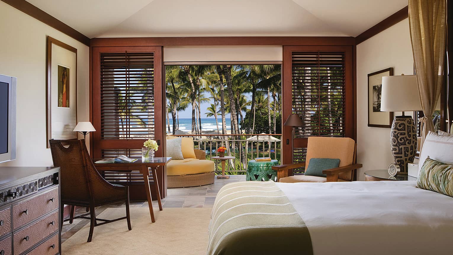 Milo Suite bed across from dresser, TV, desk and chair by open wood patio shutters