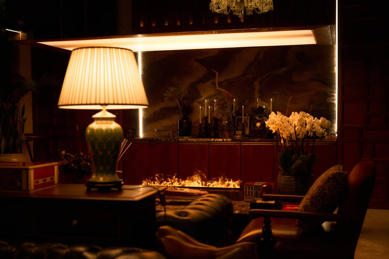Restaurant lounge area with large lamp, arm chairs and an open-flame fireplace