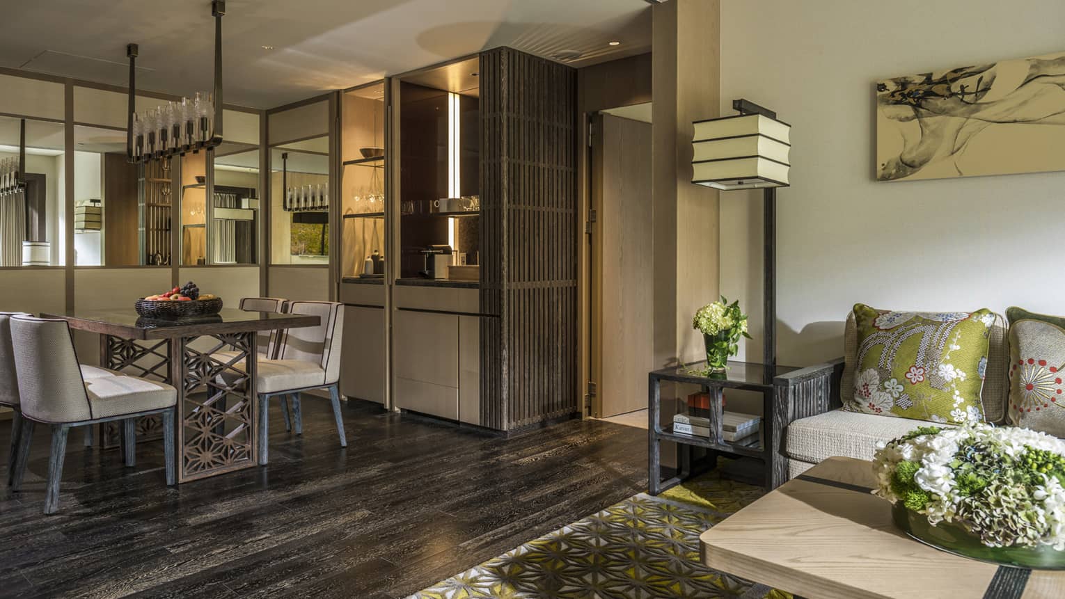 Stylish living and dining area with a modern dining table, a comfortable sofa with green accent pillows and warm lighting at Four Seasons 