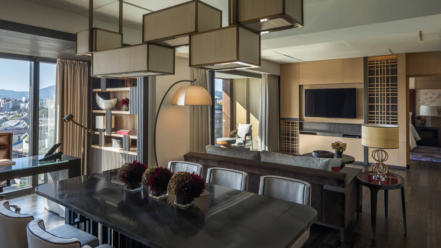 Executive desk, dining table under chandelier by back of sofa, living room